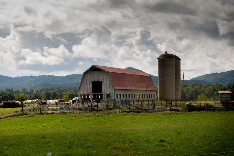 Asheville: A picturesque barn and silo in Asheville's rural landscape, nestled among rolling hills and lush fields.