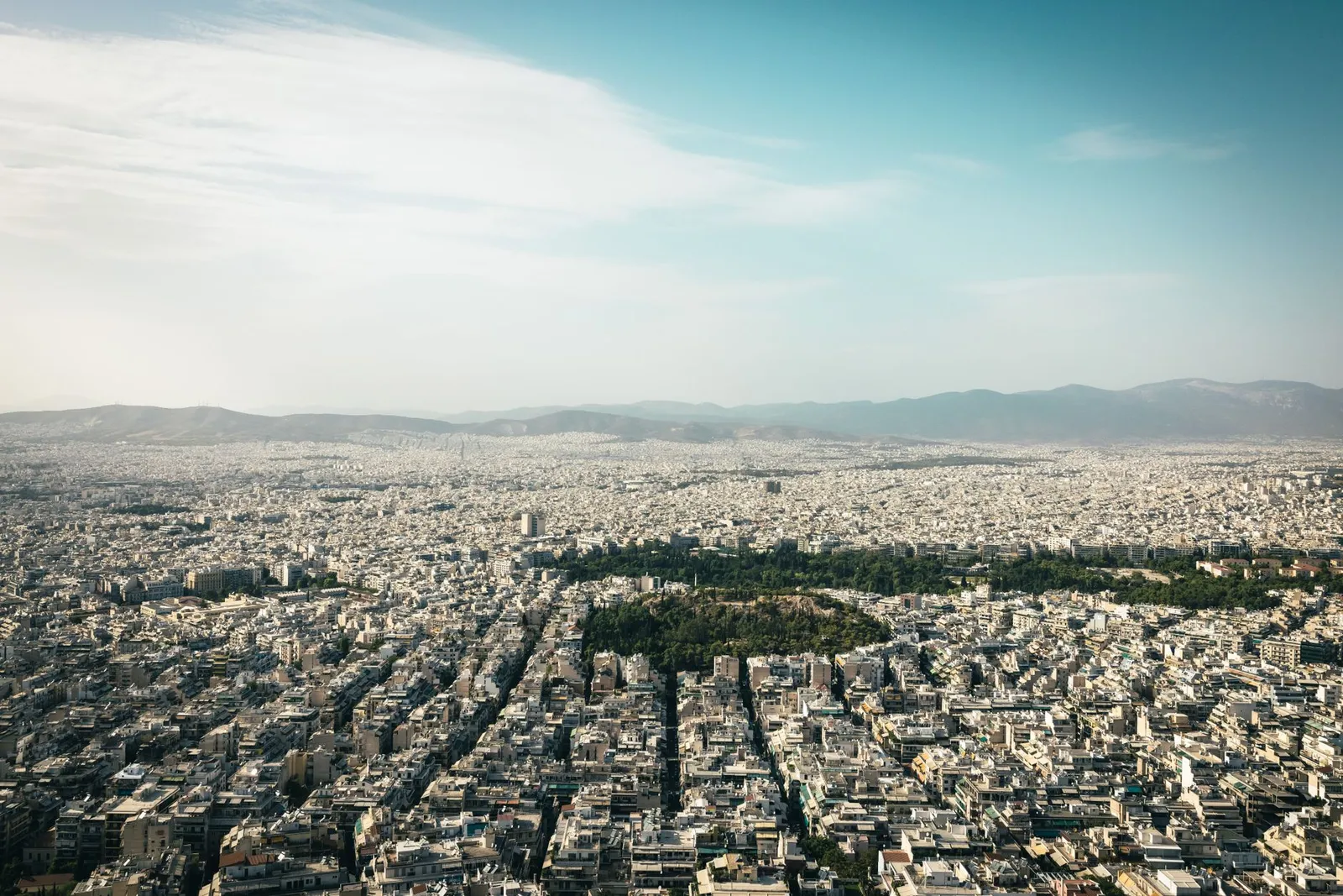 Athens: Aerial view of Athens cityscape showcasing urban density with mountains in the background.