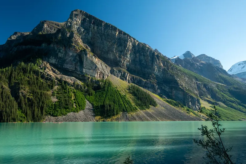 Stunning view of Lake Louise in Alberta, Canada, surrounded by the majestic Rocky Mountains and clear blue sky.
