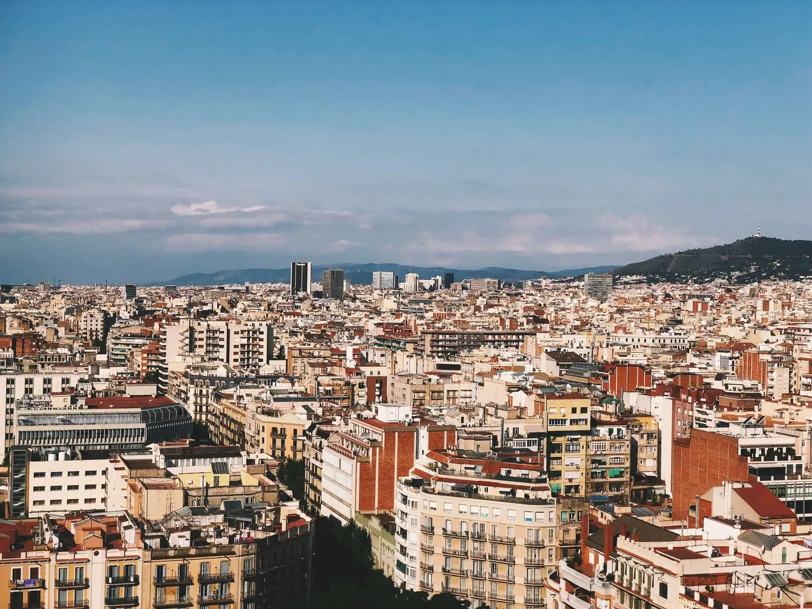 Barcelona: A panoramic view of Barcelona's colorful urban landscape with clear skies, showcasing diverse architecture.