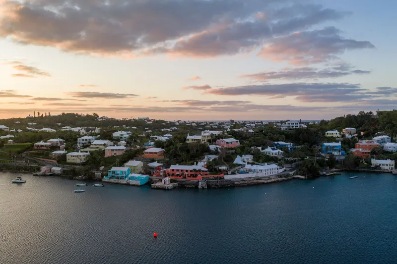 Bermuda: Aerial view of Bermuda's coastline at sunrise showcasing vibrant houses and calm waters.