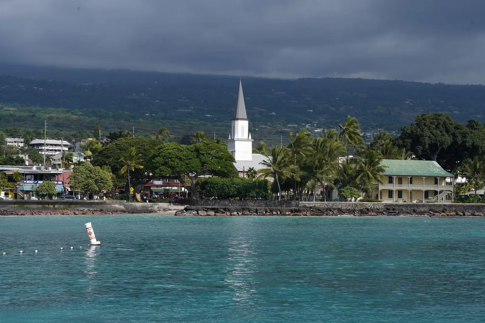 Big Island (Kona & Hilo): Scenic view of Kailua-Kona waterfront featuring a historic church under cloudy skies.