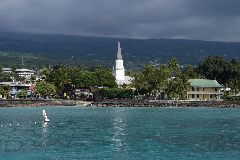 Big Island (Kona & Hilo): Scenic view of Kailua-Kona waterfront featuring a historic church under cloudy skies.