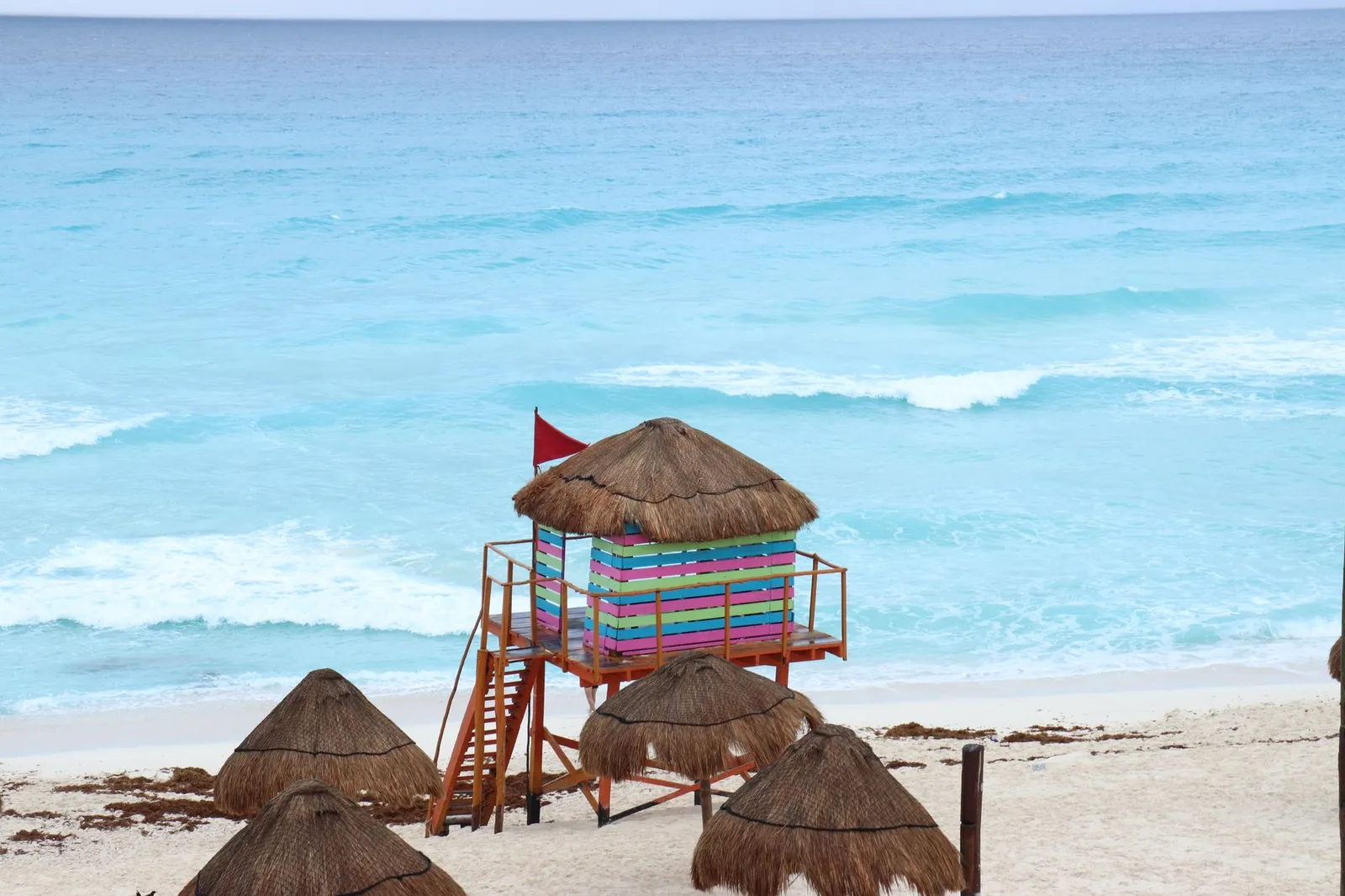 Cancún: Vibrant lifeguard tower on Cancún's sandy beach, set against turquoise ocean waves.