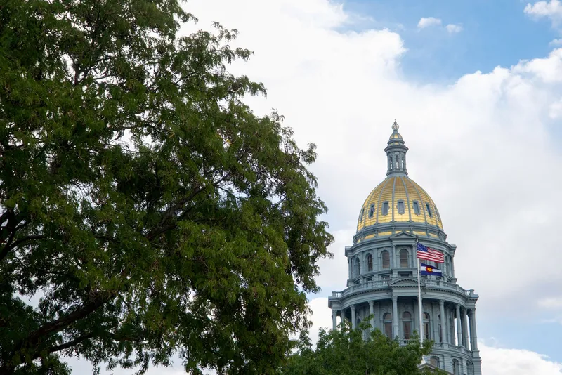 The Denver State Capitol building with its iconic gold dome under a clear blue sky.