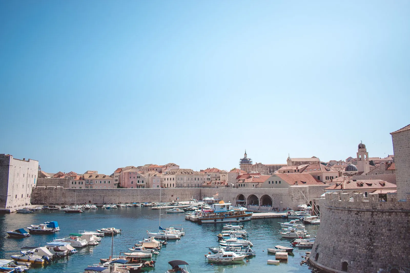 Dubrovnik: Charming view of the historic harbor in Dubrovnik, Croatia, with boats and medieval architecture.