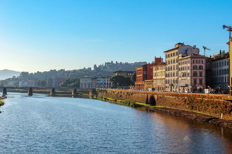 Florence & Tuscany: Scenic daytime view of the Arno River with historic buildings in Florence, Italy.