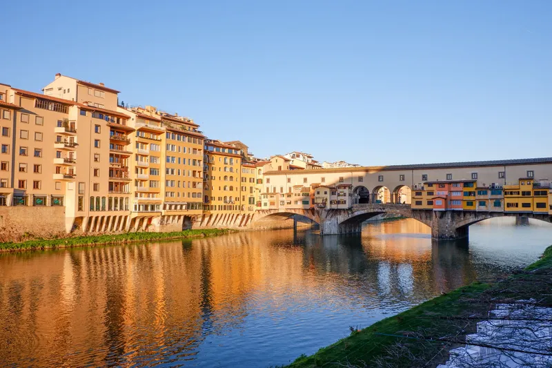 Florence & Tuscany: Beautiful sunset view of Ponte Vecchio reflected on the Arno River in Florence, Italy.
