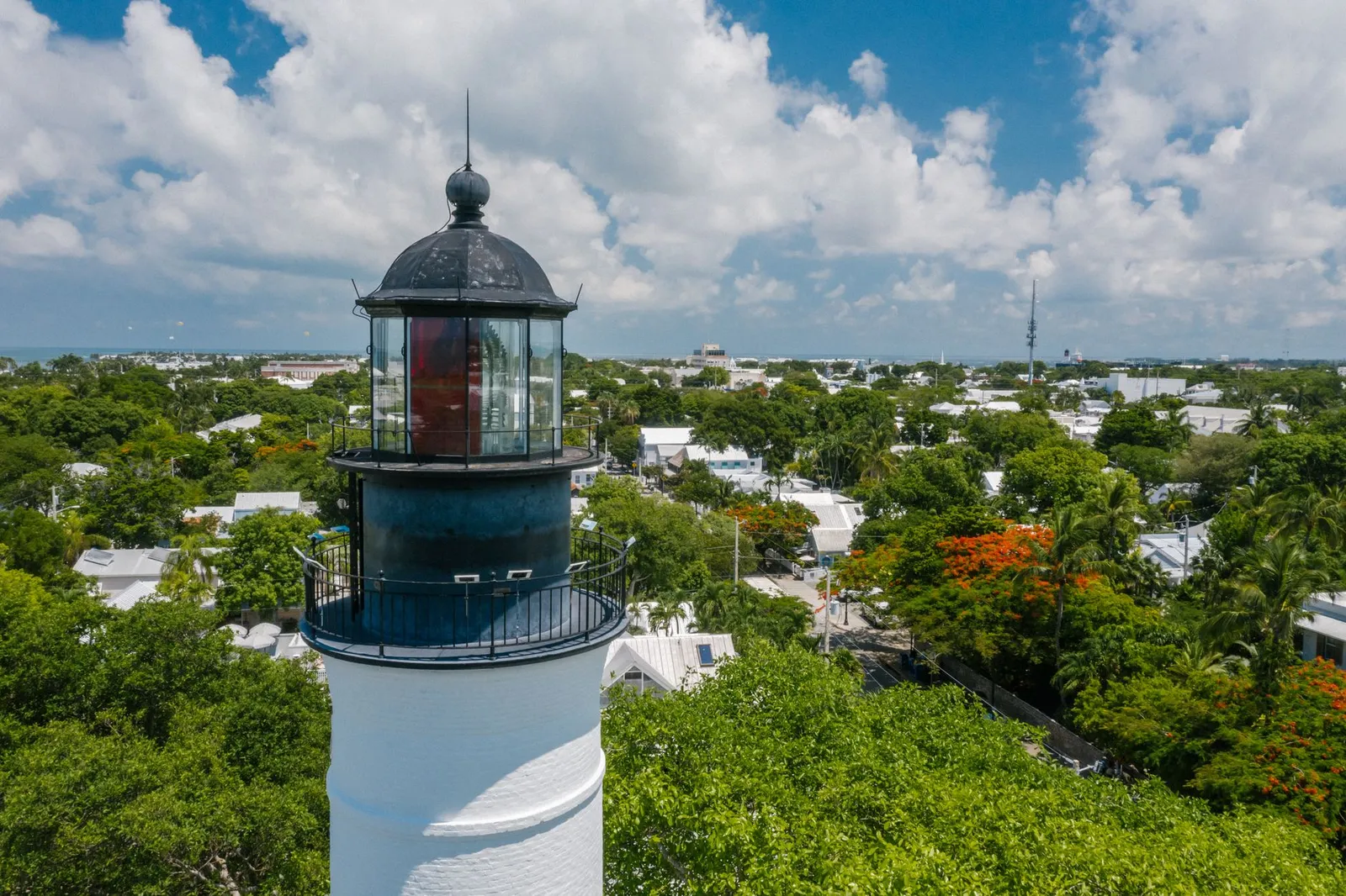 Key West: Discover the historic Key West lighthouse surrounded by lush greenery under a bright blue sky.