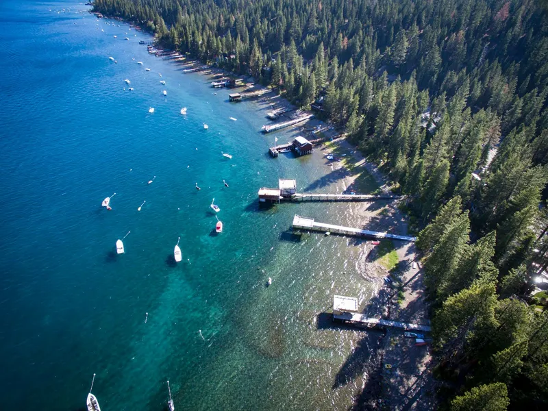 Lake Tahoe: Stunning aerial shot of Lake Tahoe's forested shoreline and boats during summer.