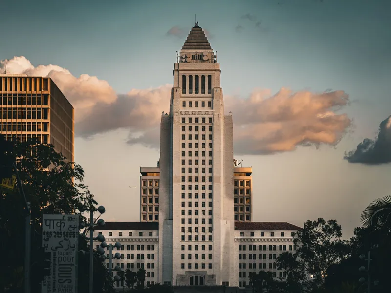 Los Angeles: Iconic Los Angeles City Hall illuminated by a dramatic sky at sunset, showcasing urban architecture.