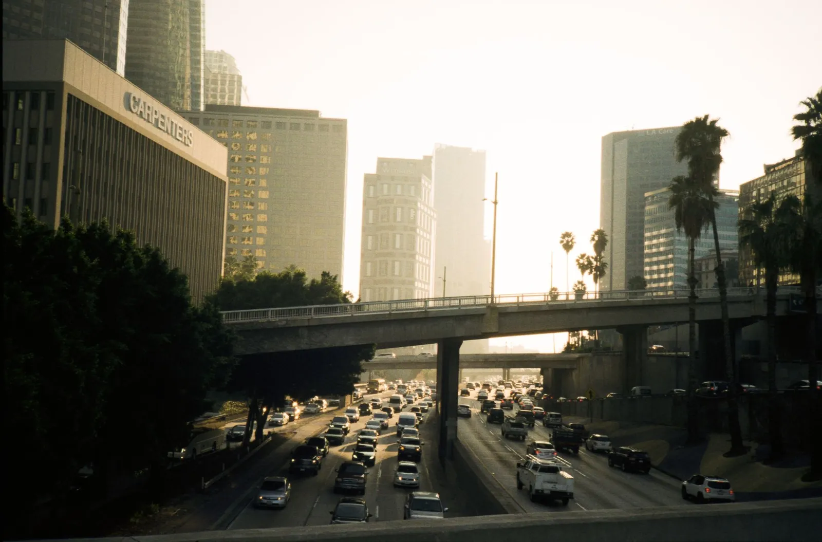 Los Angeles: Heavy traffic on a Los Angeles freeway at sunset with buildings and palm trees in view.