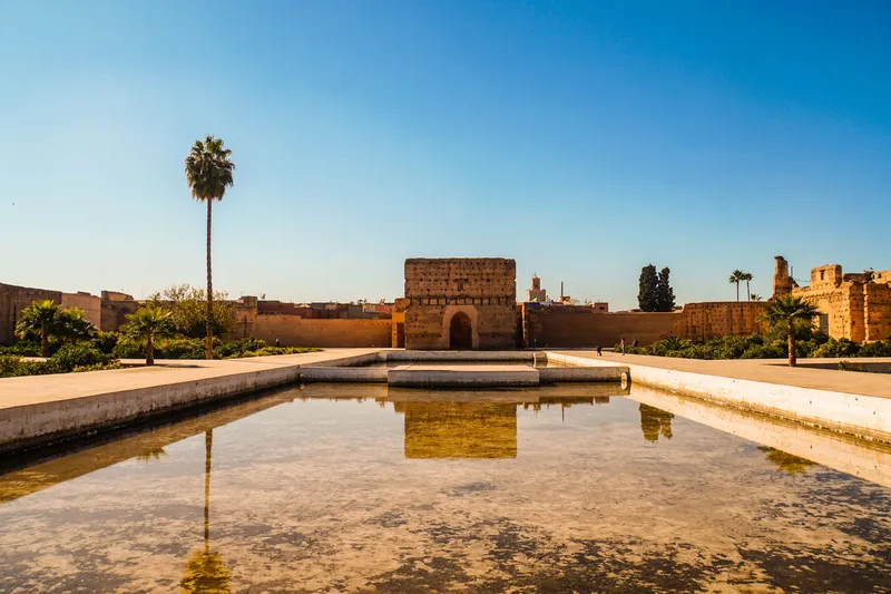 Marrakech: El Badi Palace in Marrakech under a clear blue sky with a reflecting pool in the foreground.