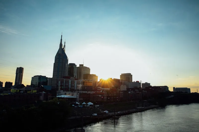 Nashville: A stunning view of Nashville's skyline at sunset, featuring a calm waterfront reflection.