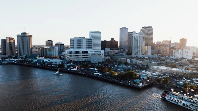New Orleans: Drone shot capturing the bustling cityscape of New Orleans and the Mississippi River at dusk.