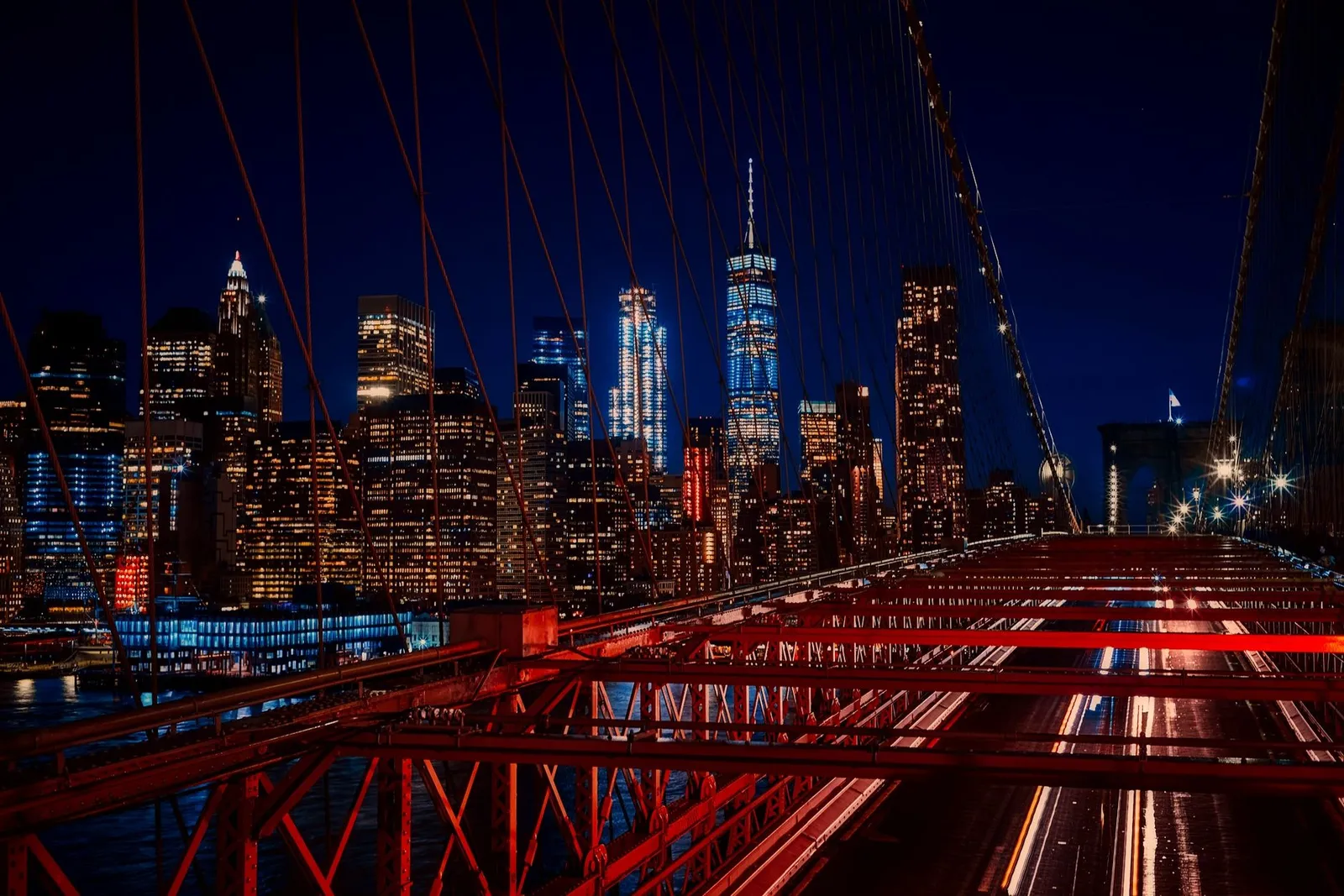 New York City: A breathtaking night view featuring the New York City skyline and iconic Brooklyn Bridge illuminated in vibrant colors.