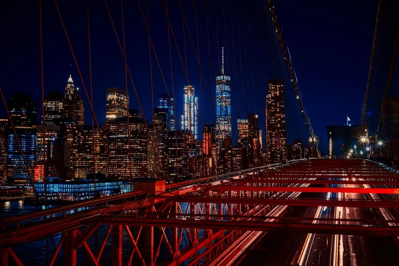 New York City: A breathtaking night view featuring the New York City skyline and iconic Brooklyn Bridge illuminated in vibrant colors.