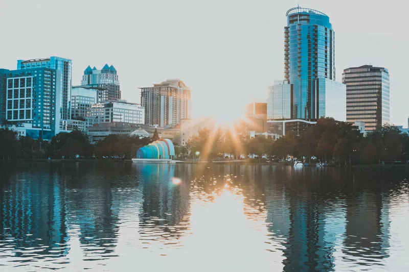 Orlando: Capture of Orlando's skyline reflecting in a lake during sunrise, showcasing urban beauty and tranquility.