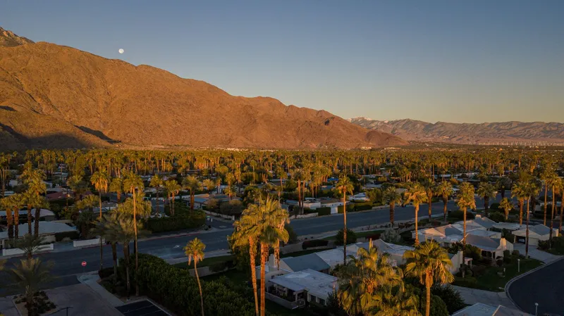 Palm Springs: Aerial view of Palm Springs showing palm trees and mountains at sunset.