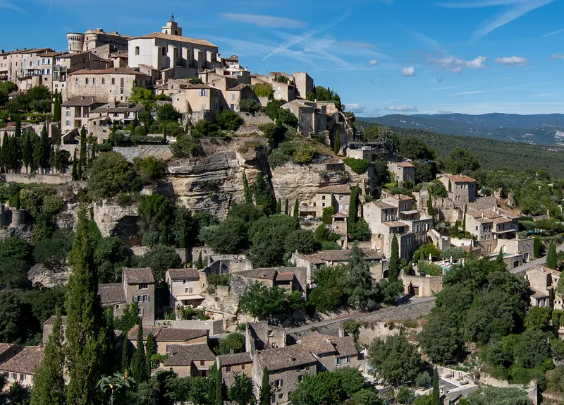 Provence: Picturesque hillside village of Gordes in Provence, showcasing historic architecture and lush greenery.