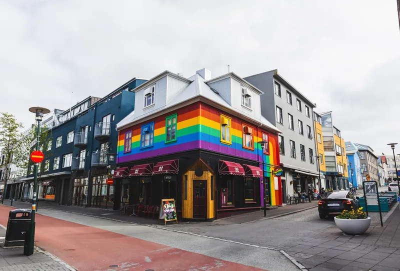Vibrant rainbow building on a Reykjavík street corner, showcasing LGBTQ inclusivity.