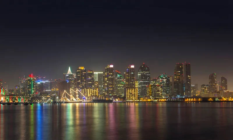 San Diego: A serene night view of San Diego's illuminated skyline reflecting on calm water.