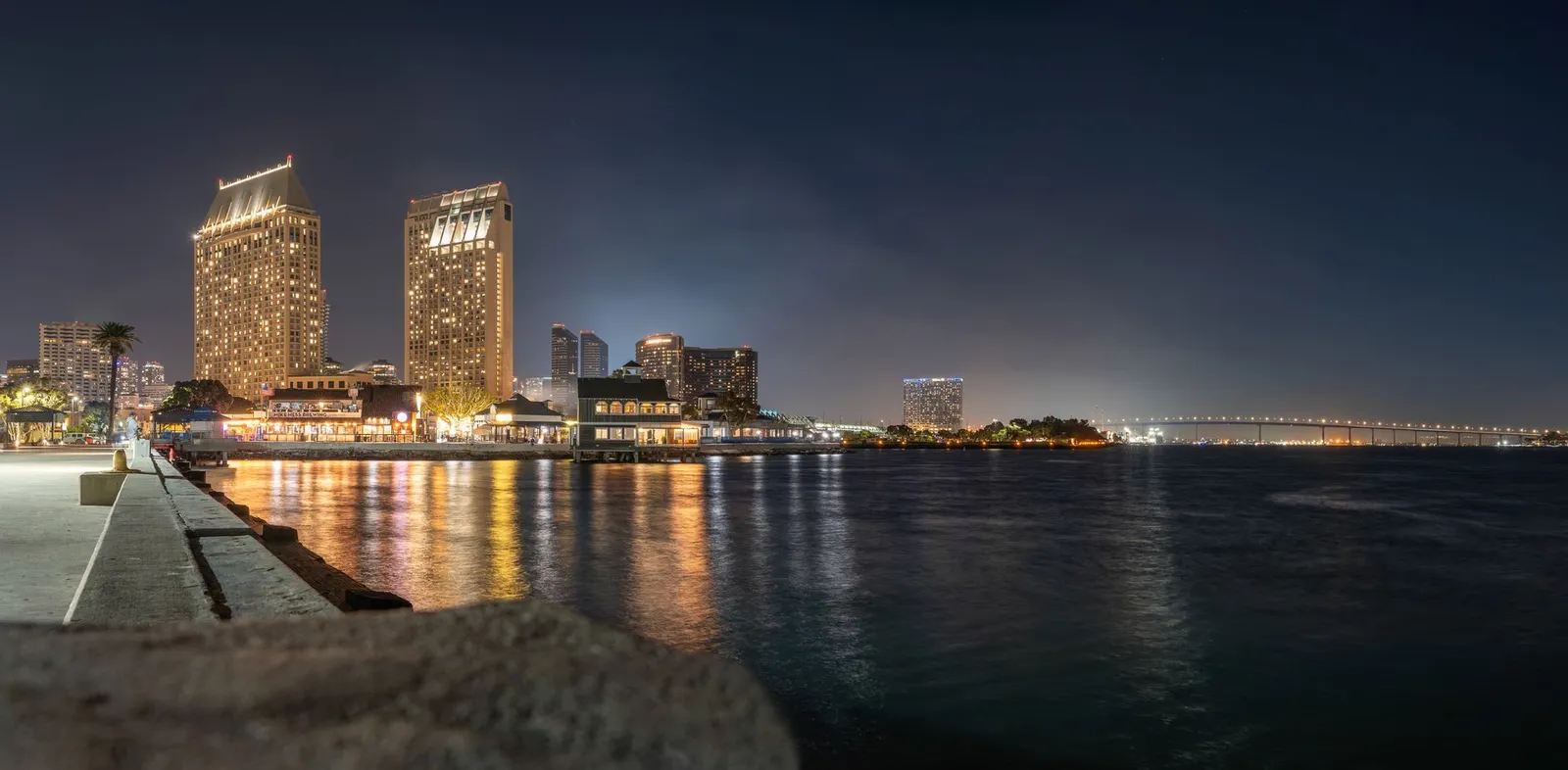 San Diego: Stunning San Diego skyline featuring Coronado Bridge and glowing city lights reflecting in the bay at night.