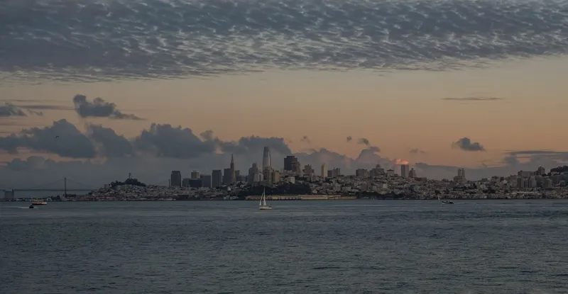 San Francisco: Beautiful view of San Francisco skyline with tranquil waters and a dramatic sunset sky.