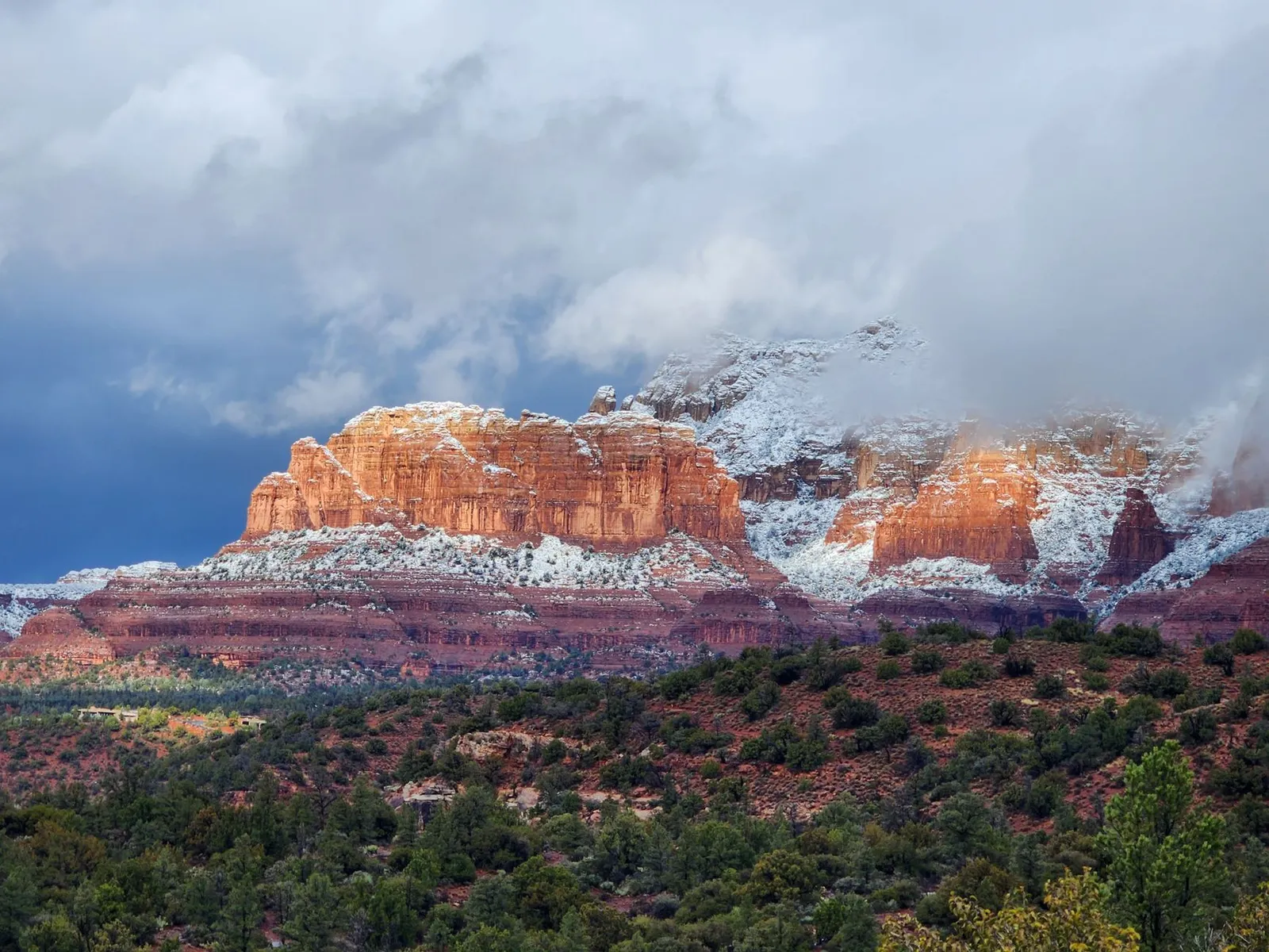Sedona: A breathtaking view of Sedona's snow-dusted red rock formations under dramatic skies, capturing winter's beauty.