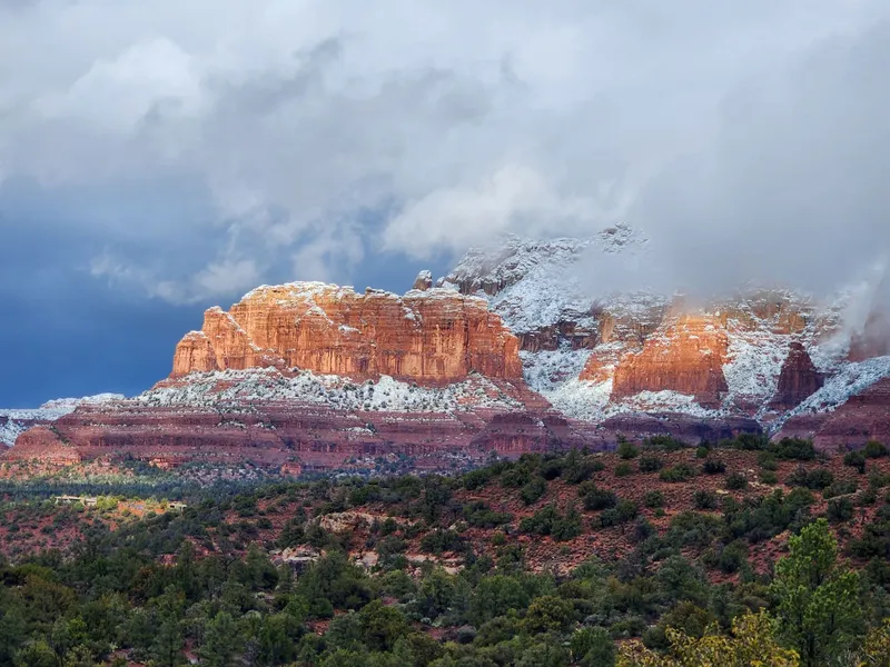 Sedona: A breathtaking view of Sedona's snow-dusted red rock formations under dramatic skies, capturing winter's beauty.