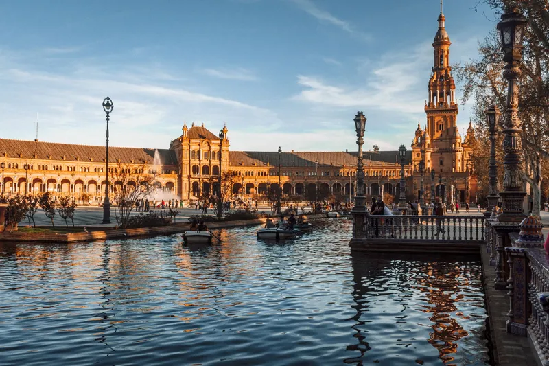 Seville: Scenic view of Plaza de España in Seville with reflections on the canal at sunset.