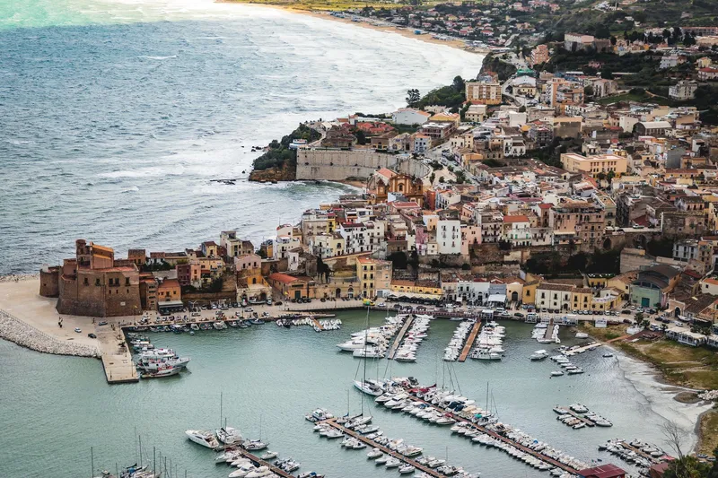 Sicily: A picturesque aerial shot of a coastal town in Sicily, showcasing the marina and historic architecture.