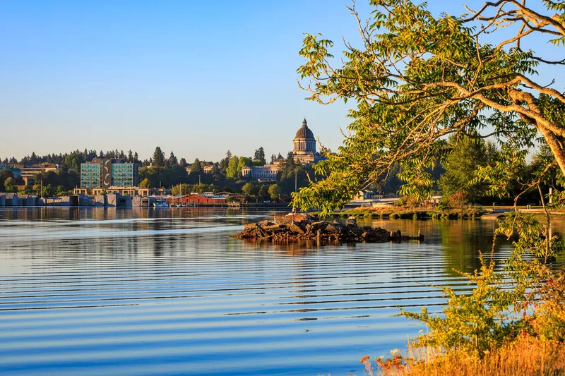 Washington, D.C.: A picturesque view of the Washington State Capitol with calm waters and vibrant greenery in Olympia.
